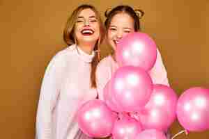 Free photo women models with pink air balloons on golden wall