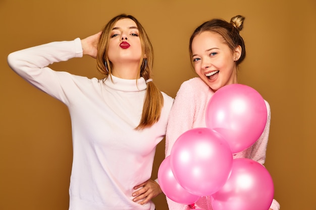 Women models with pink air balloons on golden wall