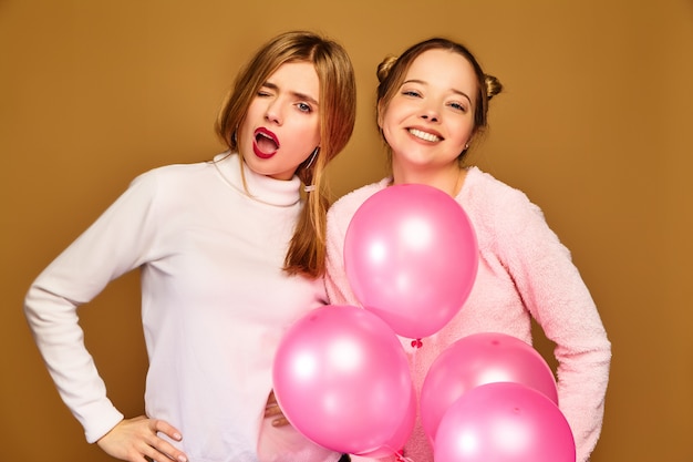 Free photo women models with pink air balloons on golden wall