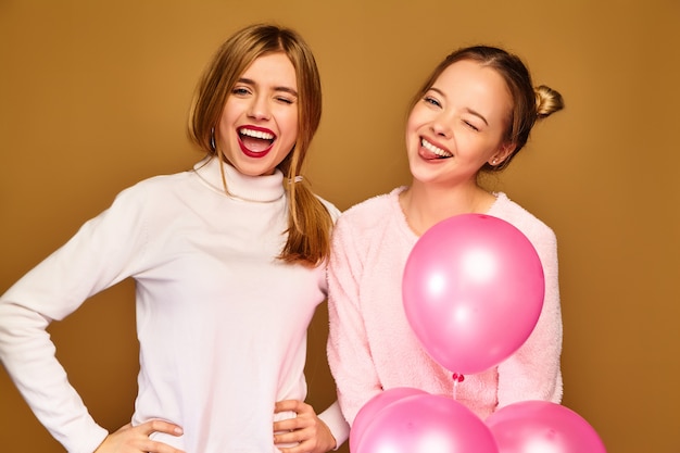 Free photo women models with pink air balloons on golden wall