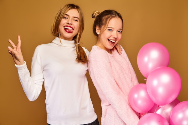 Free photo women models with pink air balloons on golden wall