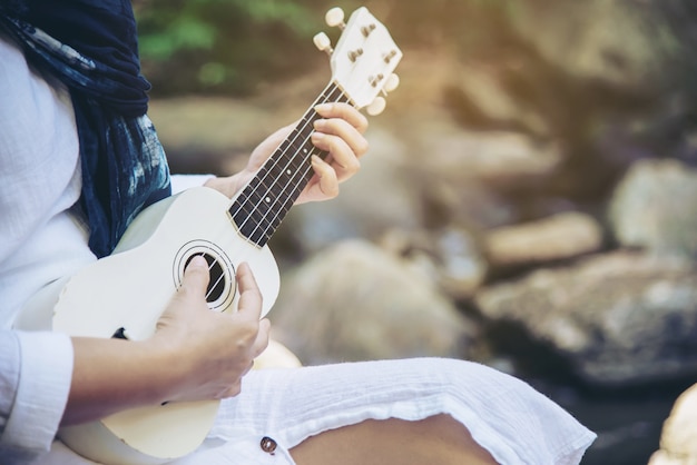 Free photo women play ukulele new to the waterfall