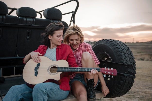 Free Photo women playing guitar while traveling by car