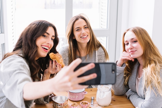 Free photo women posing for selfie with pastry