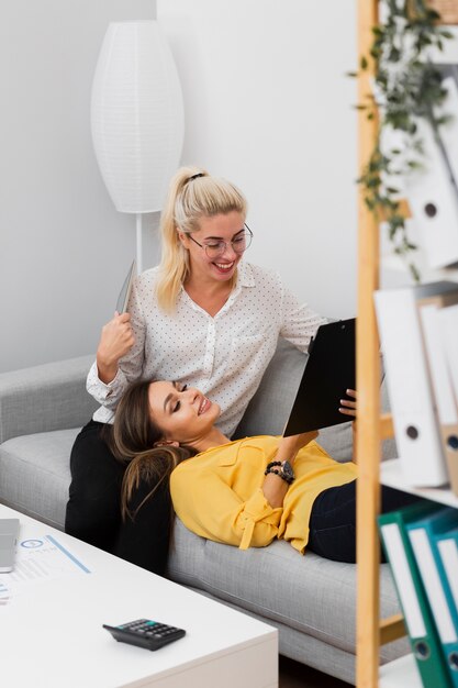 Women relaxing on a sofa and looking in a clipboard