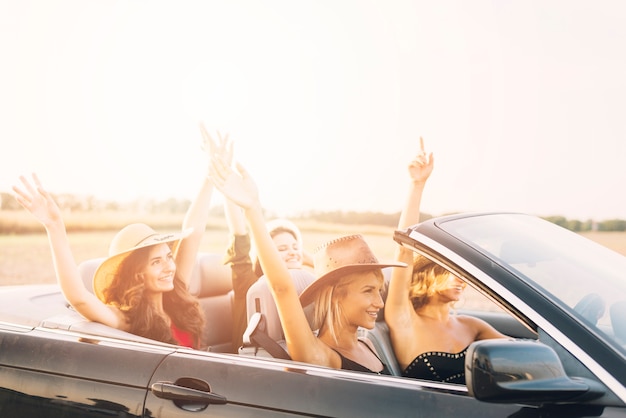 Women riding car with hands up