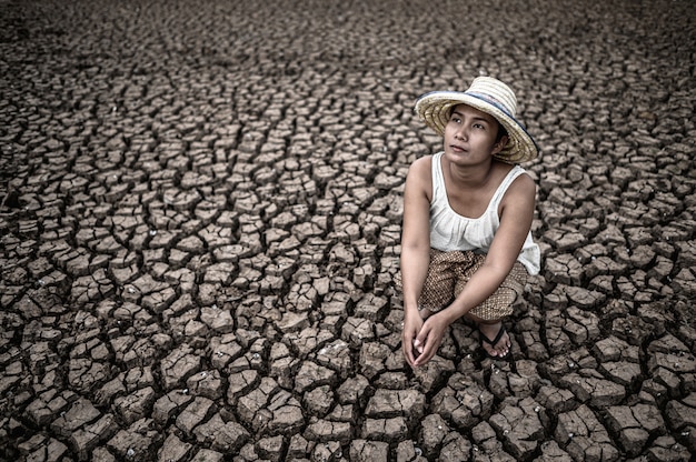 Free photo women sit looking at the sky in dry weather and global warming.