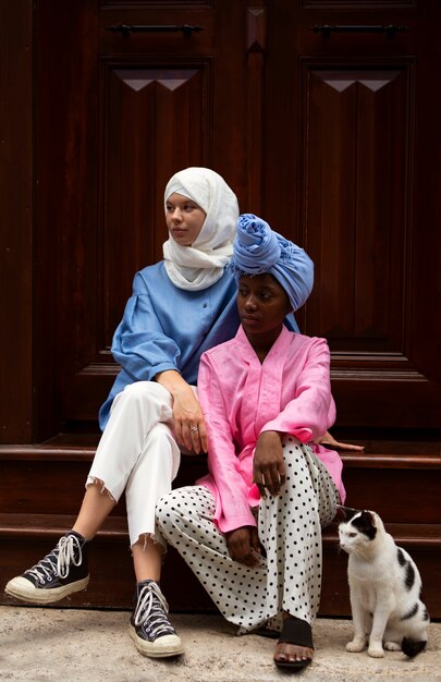 Women sitting on stairs with cat full shot