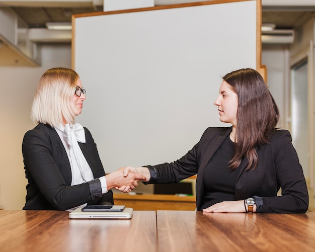 Women sitting at table shaking hands