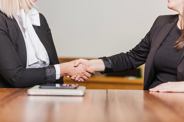 Free photo women sitting at table shaking hands