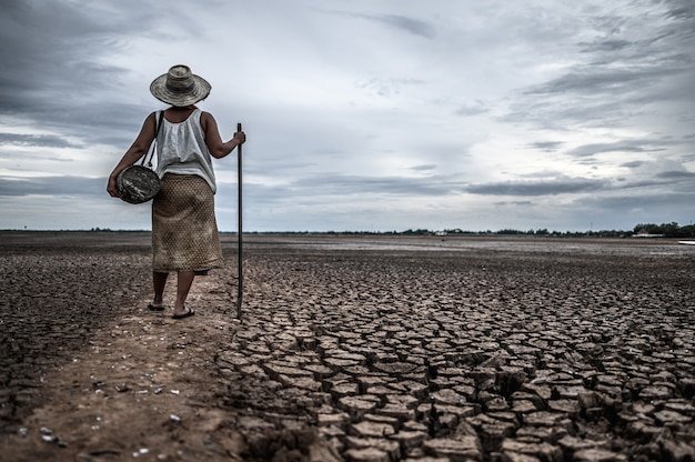 Free photo women standing on dry soil and fishing gear, global warming and water crisis