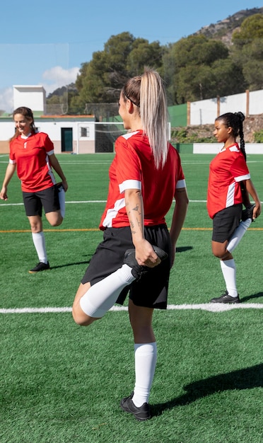 Free Photo women stretching leg on football field