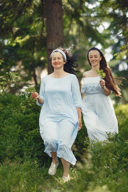 Women in a summer forest. Lady in a blue dress. Family posing and embracing.