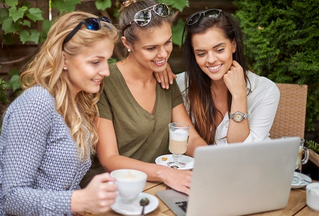 Free photo women taking a coffee with friends and using a laptop