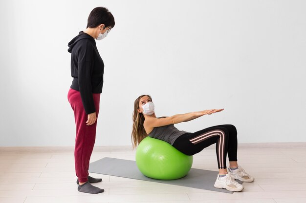 Women training on a fitness ball while wearing medical masks