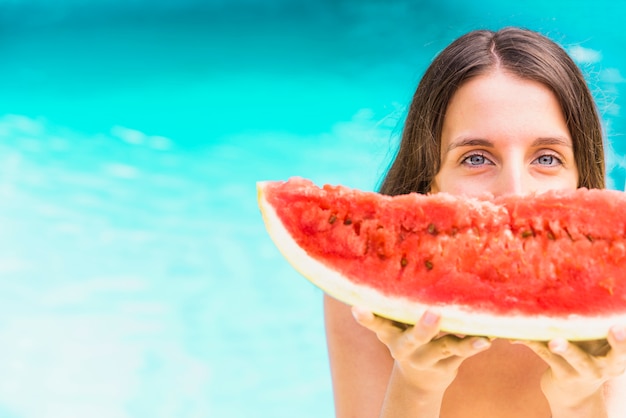 Women with watermelon standing near swimming pool