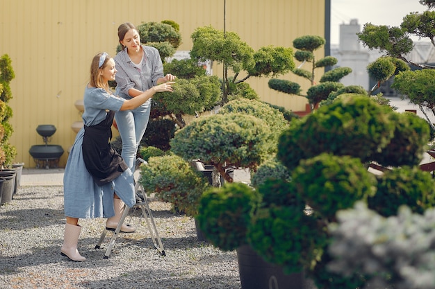 Women working in a greenhouse with green trees