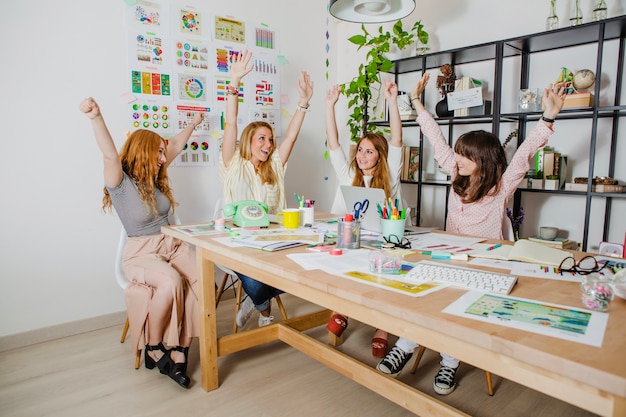 Women at workplace with hands up