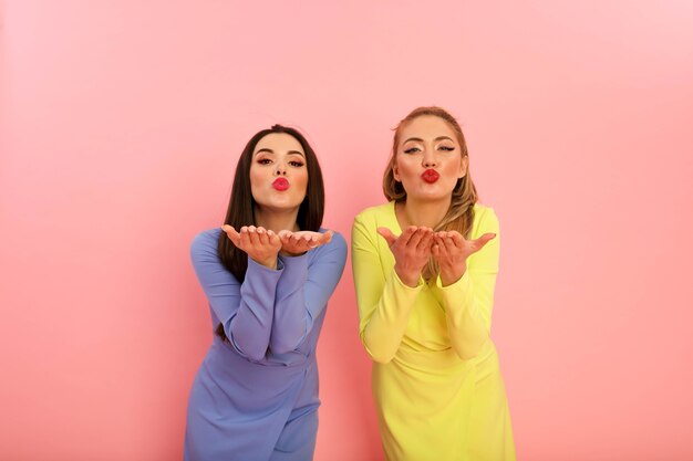 Wonderful bright ladies in summer stylish dresses, yellow and blue. Blonde and brunette with big red lips and modern hairstyle. Shapely hot bodies, sexy models.Shooting in studio on the pin background