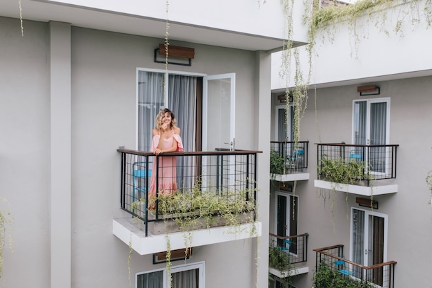 Free Photo wonderful caucasian girl expressing happiness while posing in hotel. carefree curly tanned woman in pink dress.