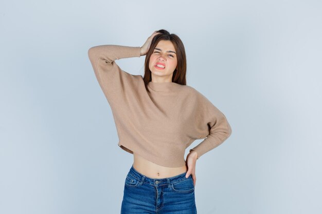 Wonderful lady suffering from headache in sweater, jeans and looking unwell. front view.