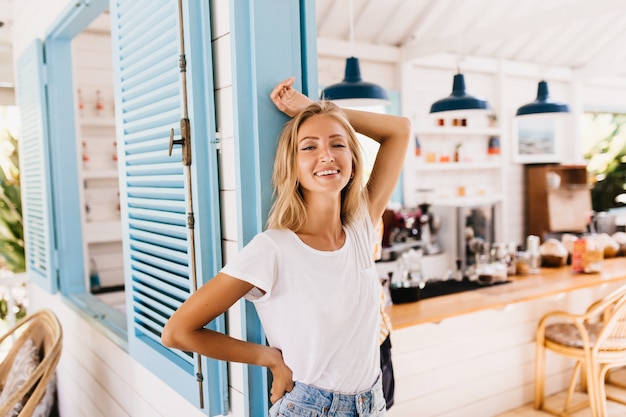 Wonderful lightly-tanned woman in retro jeans posing with positive smile.