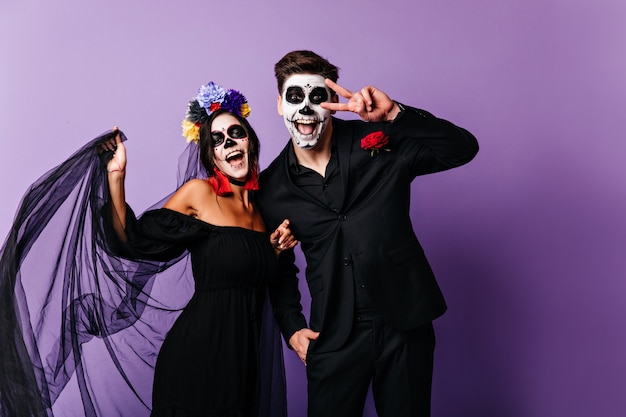 Wonderful mexican zombies expressing happiness. Charming muerte girl celebrating halloween with boyfriend.