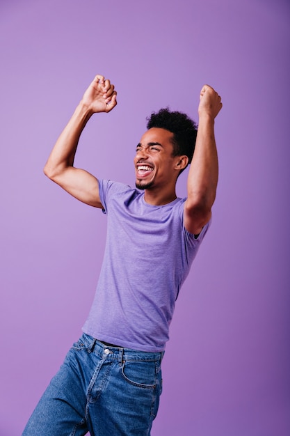 Wonderful strong guy screaming. Indoor shot of happy african man in casual t-shirt.