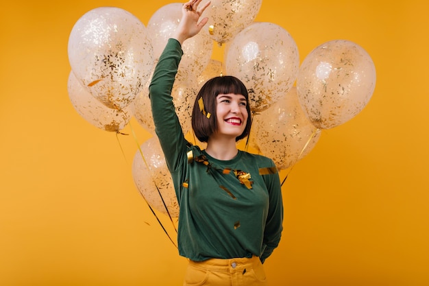 Free photo wonderful young lady posing emotionally in her birthday. laughing black-haired girl enjoying party.