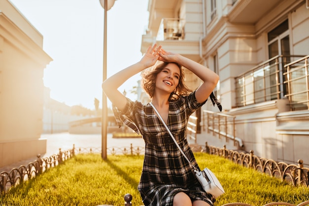 Free photo wonderful young woman posing in sunny autumn day. laughing fashionable white lady relaxing in september morning.