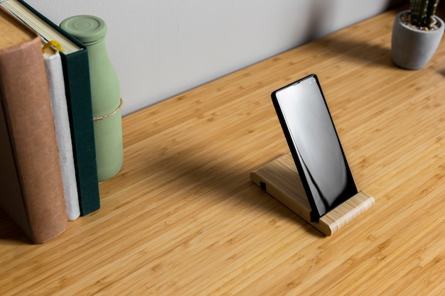 Free photo wood desk with black smartphone and books