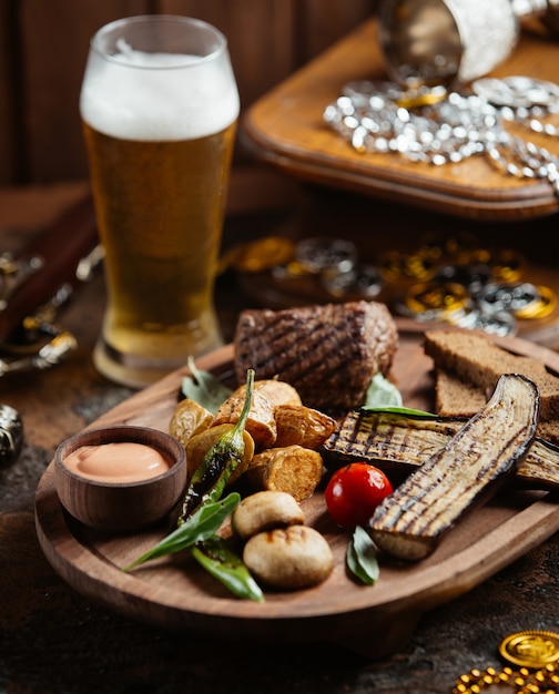 Free photo wood platter of beef steak with grilled aubergine, potato, mushroom and sauce