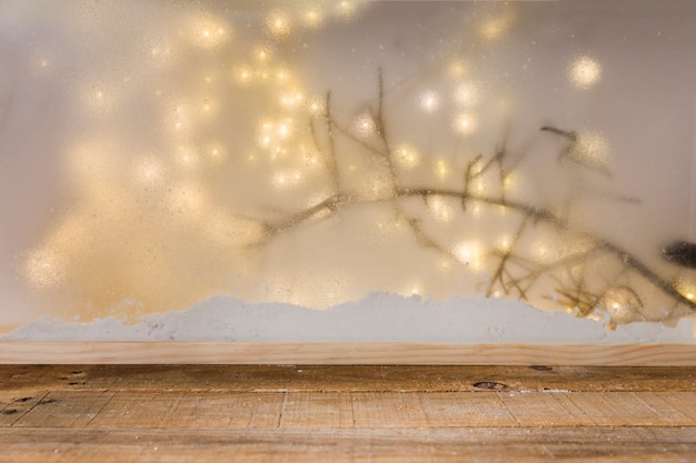 Free photo wood table near bank of snow, plant twig and fairy lights