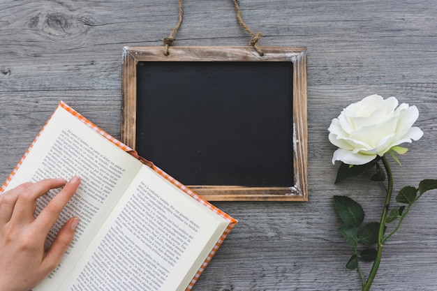 Free photo wooden background with open book, slate and flower