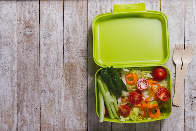 Wooden background with salad and cutlery