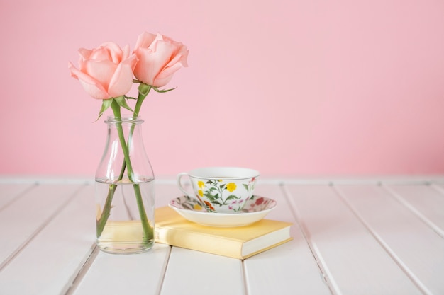 Wooden background with vase, coffee cup and book