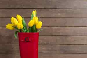 Free photo wooden background with water boot and yellow tulips