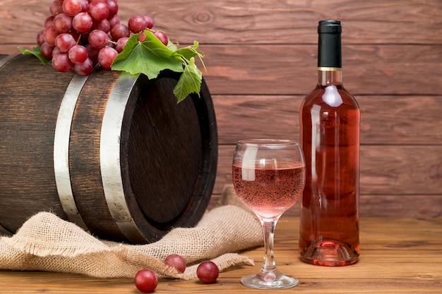 Free photo wooden barrel with bottle and glass of wine