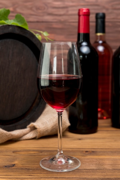 Free photo wooden barrel with bottle and glass of wine