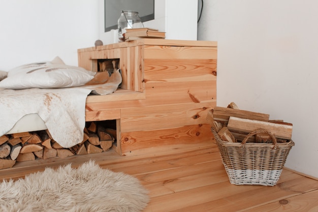 Free photo wooden bed and firewood under it, basket full of fireplace