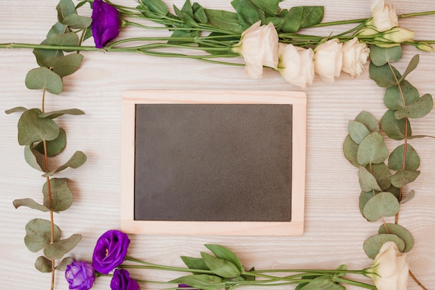 Wooden blank slate decorated with eustoma flowers on wooden background