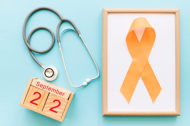 Wooden block calendar 22nd September, stethoscope and orange ribbon for multiple awareness