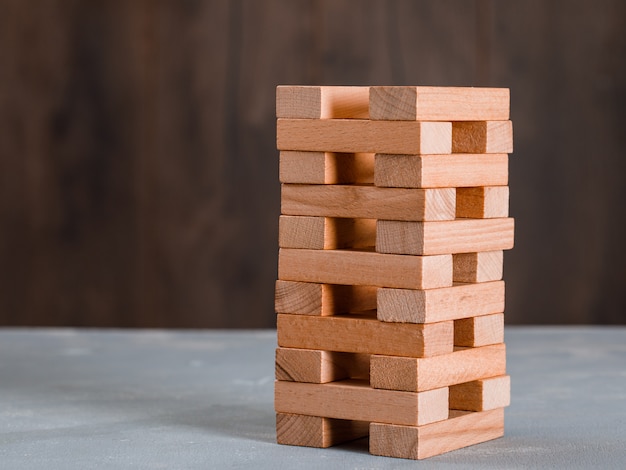 Free photo wooden block tower on wooden and plaster table