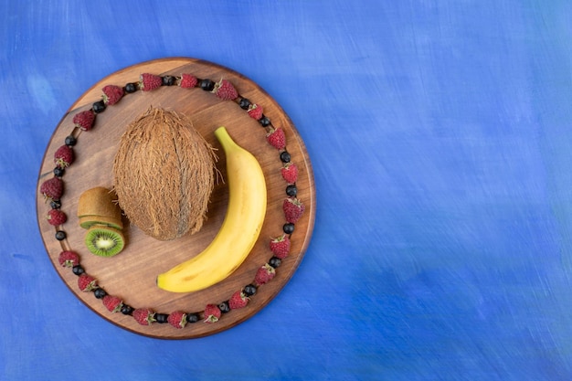 A wooden board of coconut, kiwi and banana