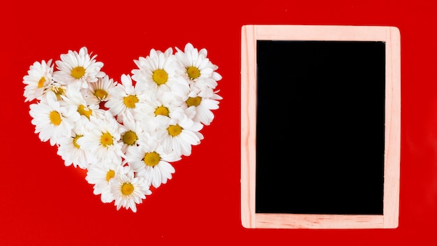 Free photo wooden board and daisy flowers in heart shape