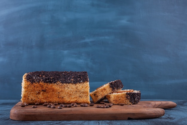 Wooden board of delicious sponge cake on marble background. 