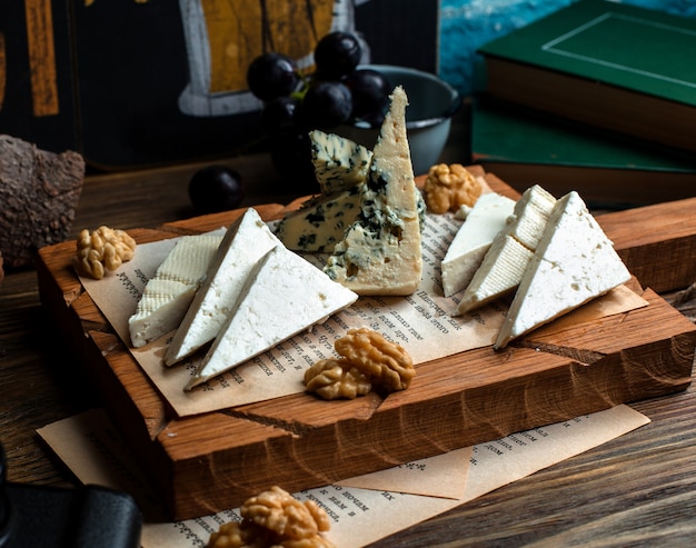 Free photo wooden board of different cheeses and walnuts