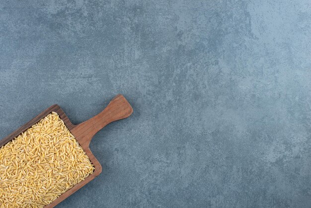 Wooden board filled with wheat grain on marble