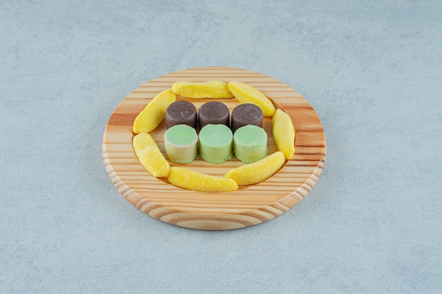 A wooden board full of banana shaped chewing candies and jelly sweets