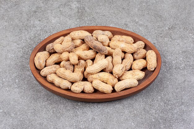 A wooden board full of healthy peanuts in shell